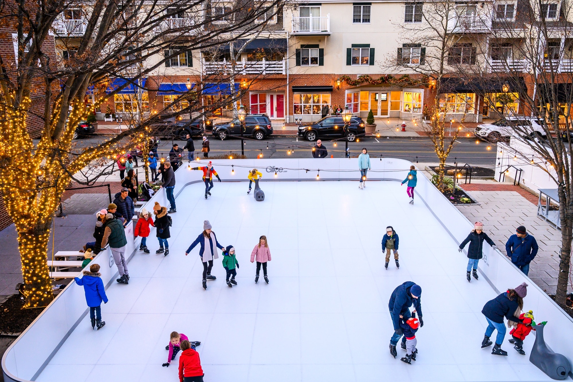 Families skating on an outdoor rink at Palmer Square, surrounded by shops