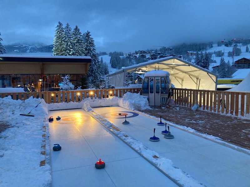 Outdoor synthetic curling lanes at a snowy hospitality venue