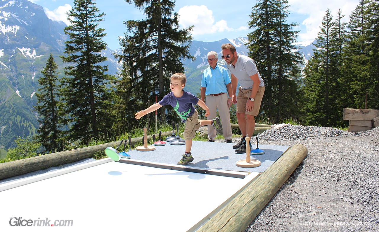 Child playing Eisstock in the Swiss Alps with family