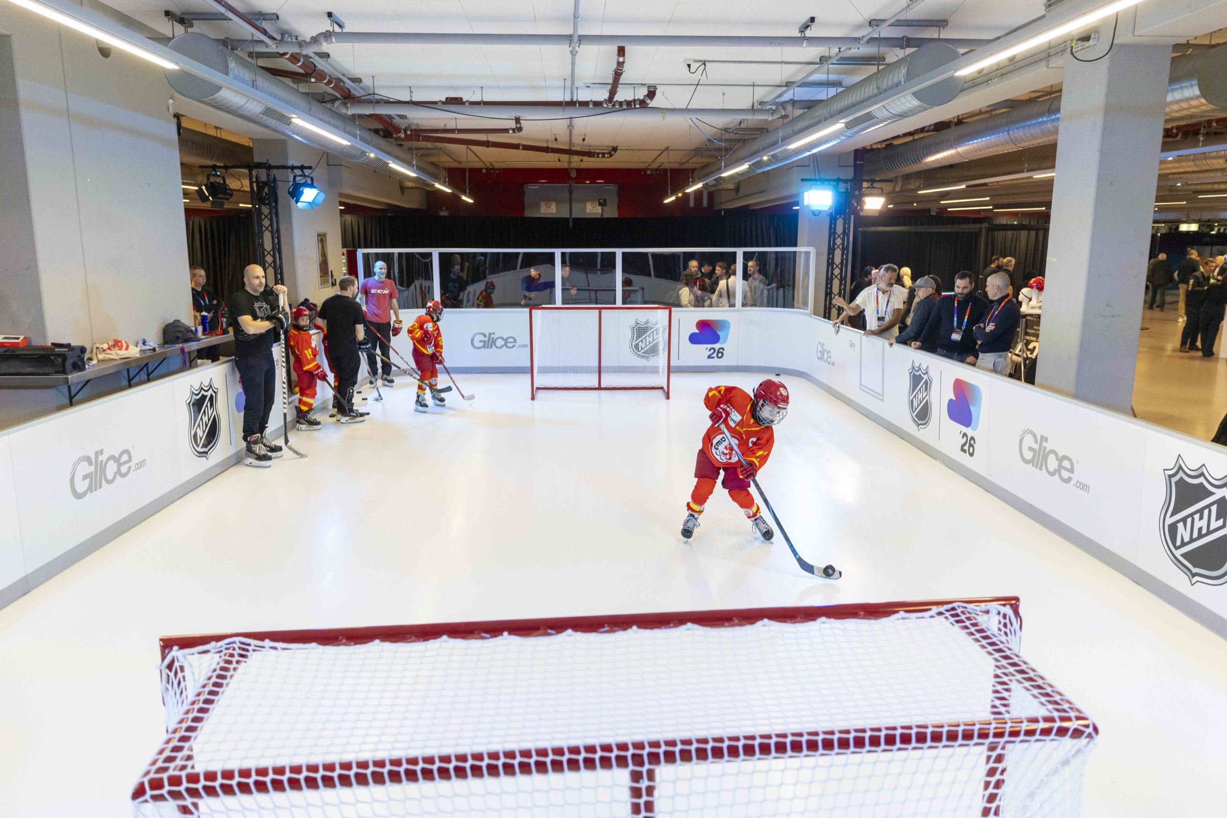 Düsseldorfer EG-spillere på den Glice syntetiske isbanen mens besøkende ser på fra bak vantet på Sports Innovation Conference 2026
