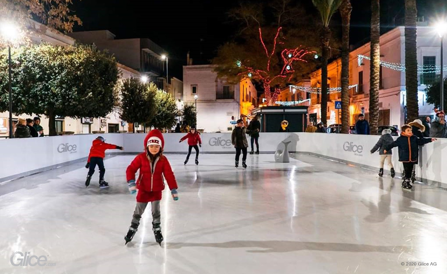 Families skating at an illuminated municipal rink in a town square