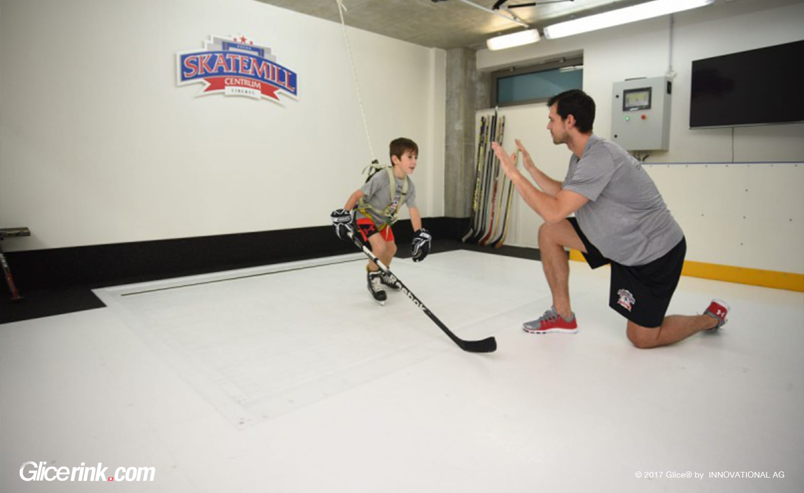 Coach training young hockey player on Glice Skatemill