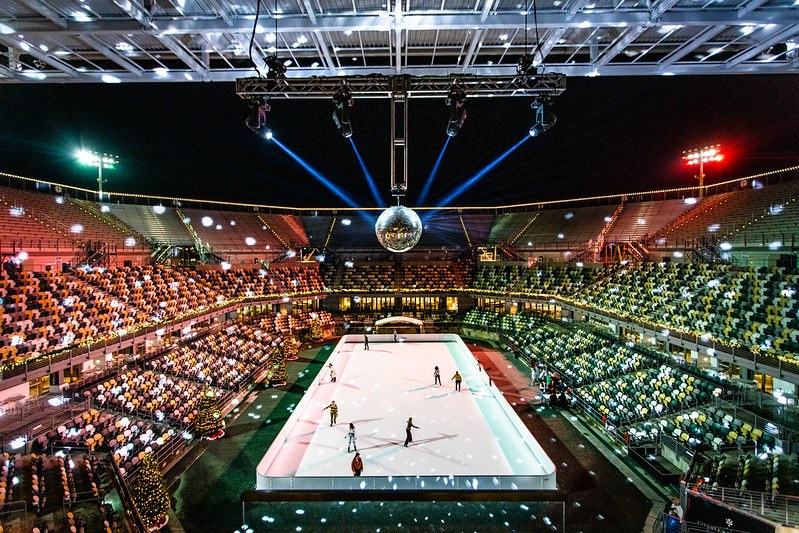 Lodowisko Skate the Stadium Glice na Credit One Stadium pod kulą dyskotekową i kolorowymi światłami