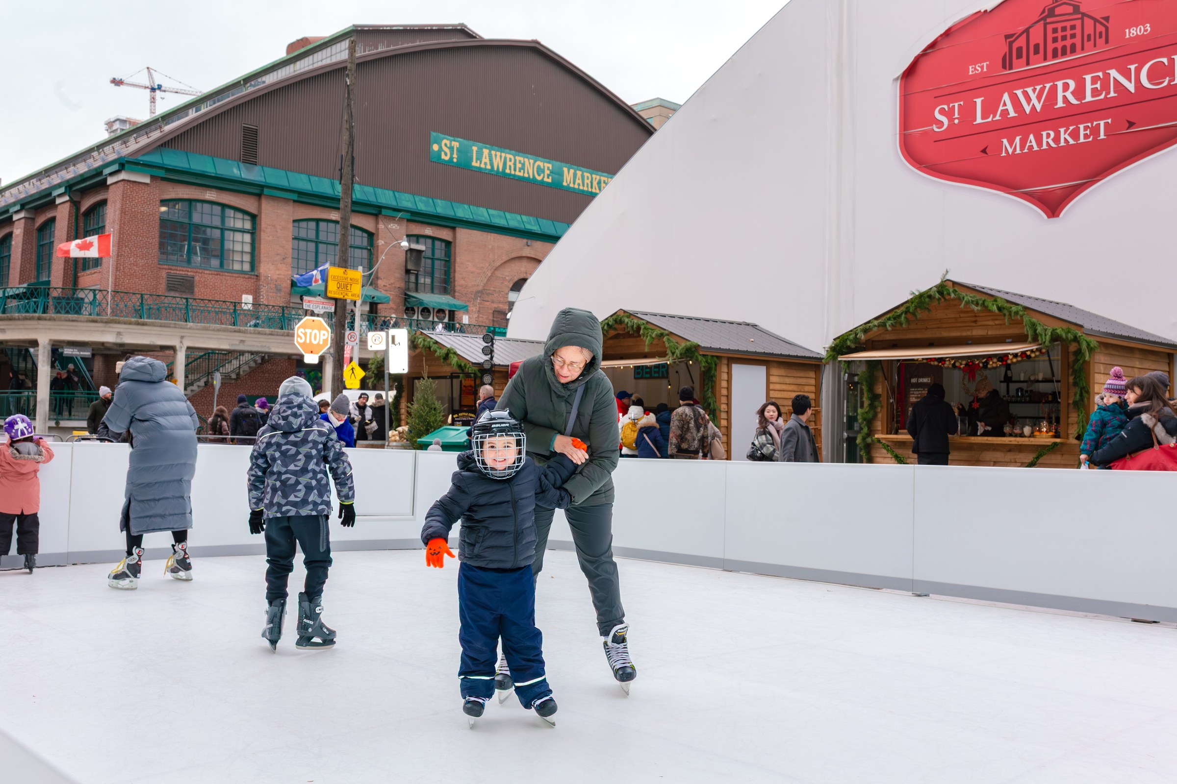 Rodziny jeżdżące na łyżwach przed St. Lawrence Market na Winter Market organizowanym przez miasto Toronto