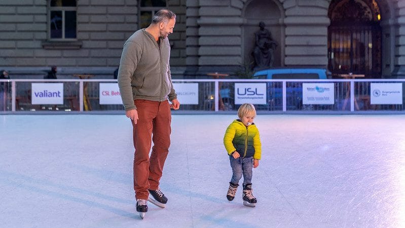 Father and son skating on synthetic ice rink in Switzerland