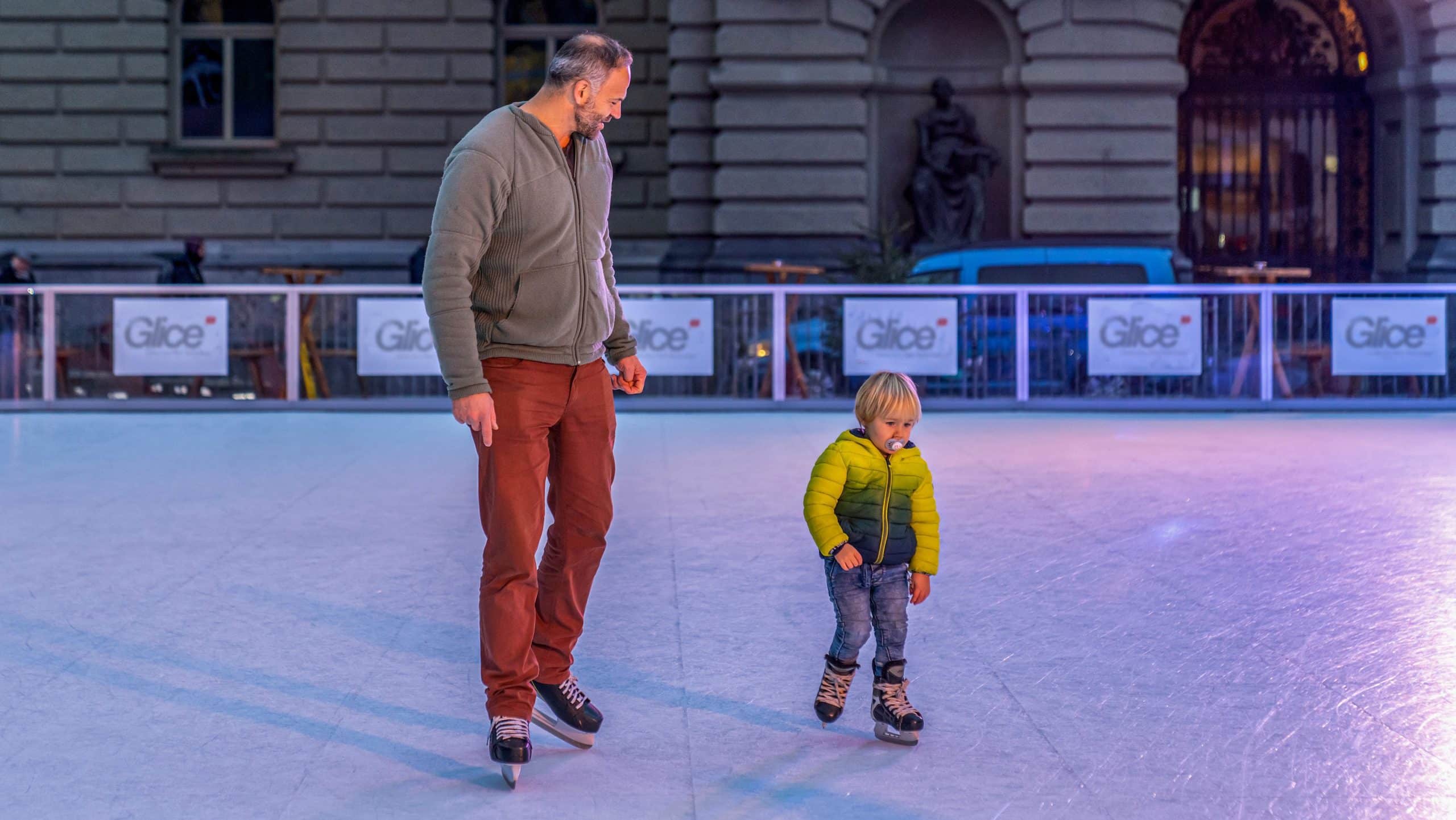 Vater und Sohn beim Eislaufen auf Schweizer Eisbahn