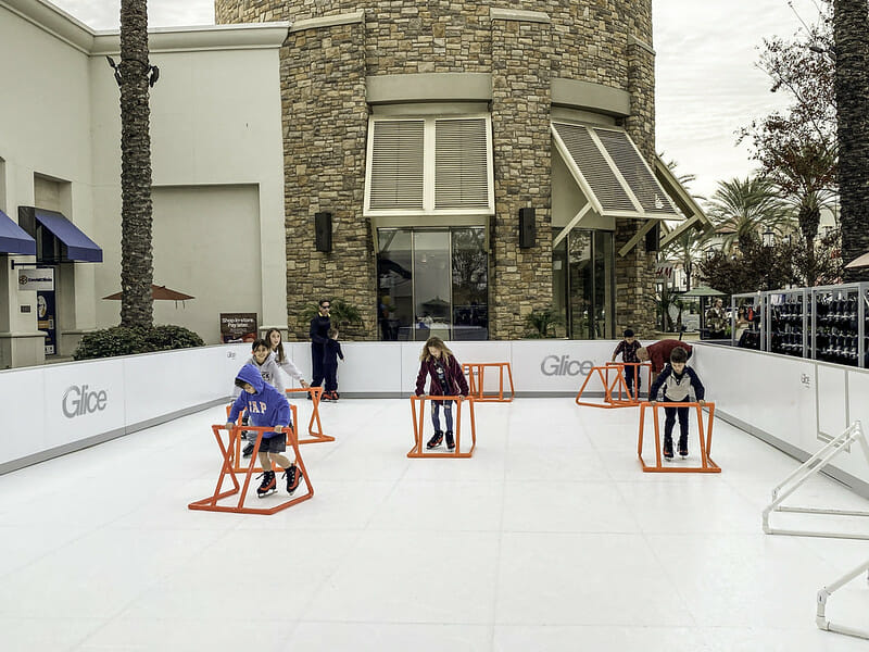 Kids on synthetic ice with skating aids