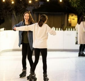 Two girls ice skating together