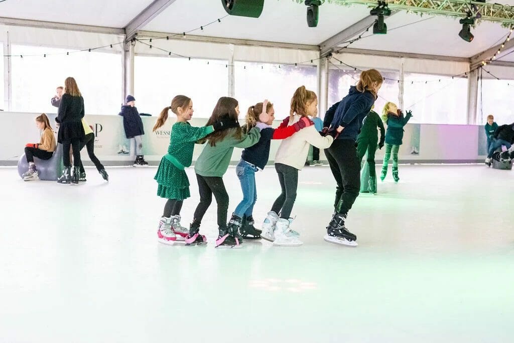 Children skating in a line on a Glice rink in Nuenen, Netherlands