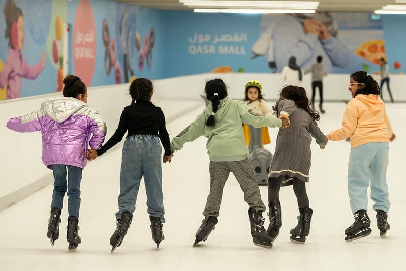 Kids ice skating hand in hand