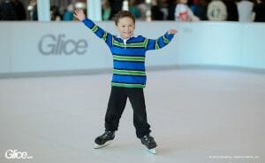 Smiling little boy skating on synthetic ice