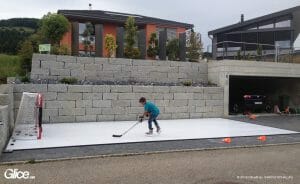 Young boy practicing hockey on backyard synthetic ice rink