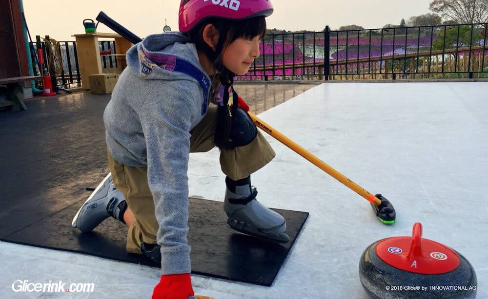 Young child curling on synthetic ice rink